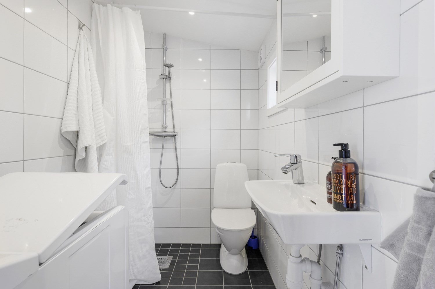 Lågupplöst Nybyggt badrum med tvättmaskin och värmegolv samt takspottar.